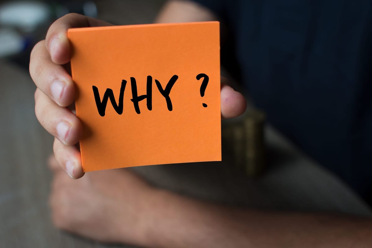 Hand holding an orange Paper with the word why - Why?, Business Concept